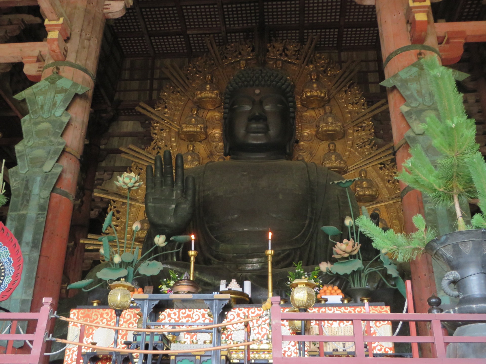 Large Buddha statue with intricate gold design and alter in front
