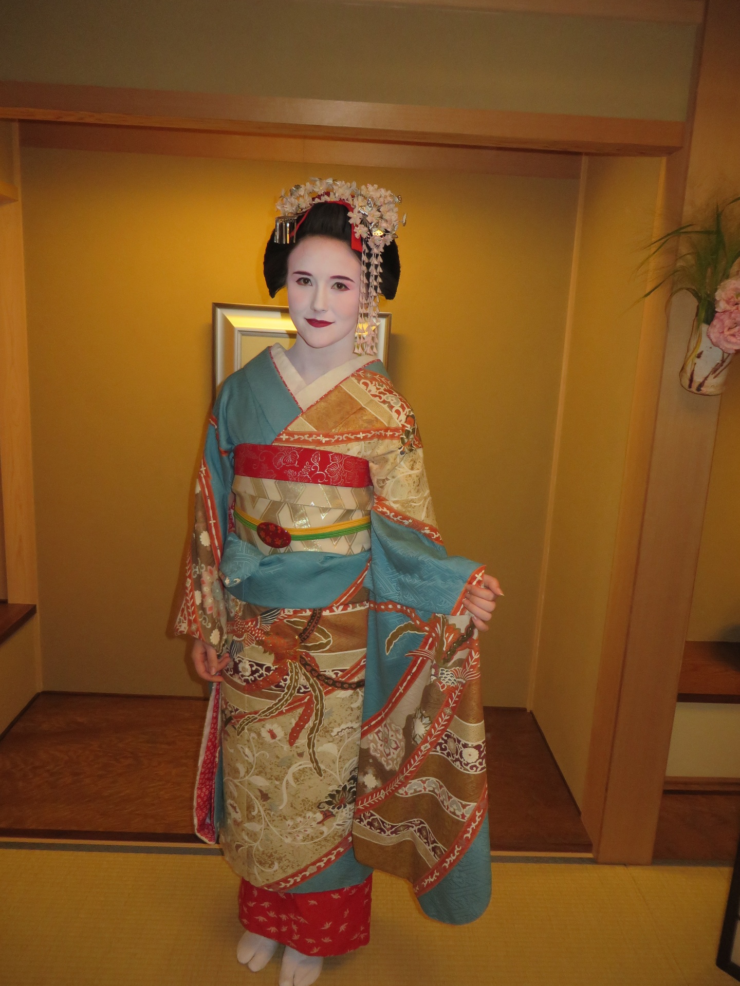 A woman dressed as a traditional geisha wearing make up and traditional headdress