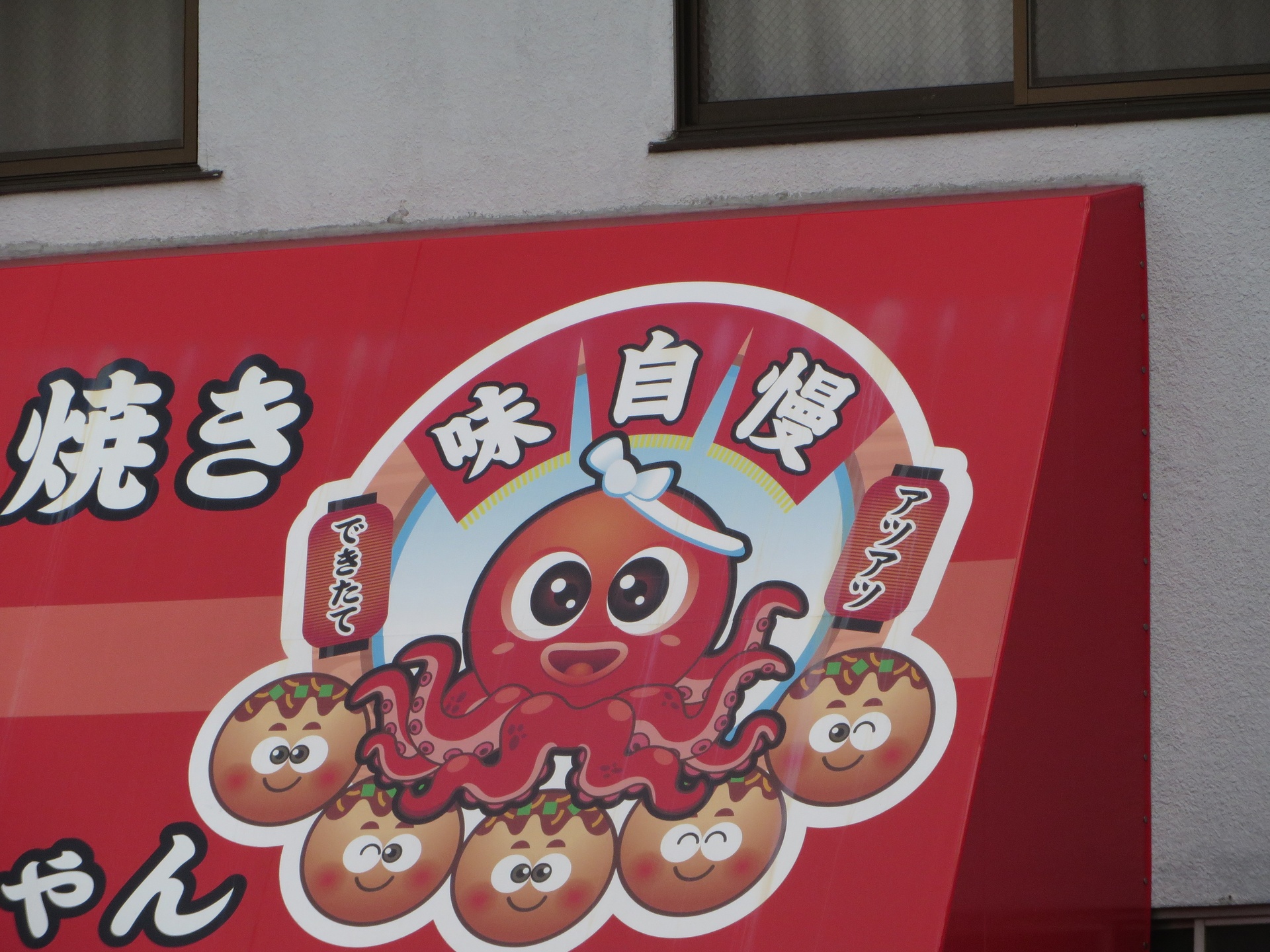 Cute red octopus sign with lanterns and food symbols on side of building